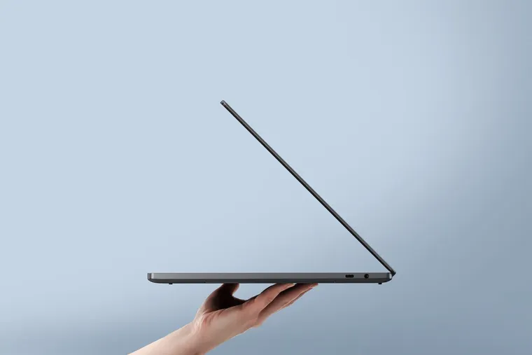 An XPS 14 held open on one hand, seen edge-on to show how thin it is